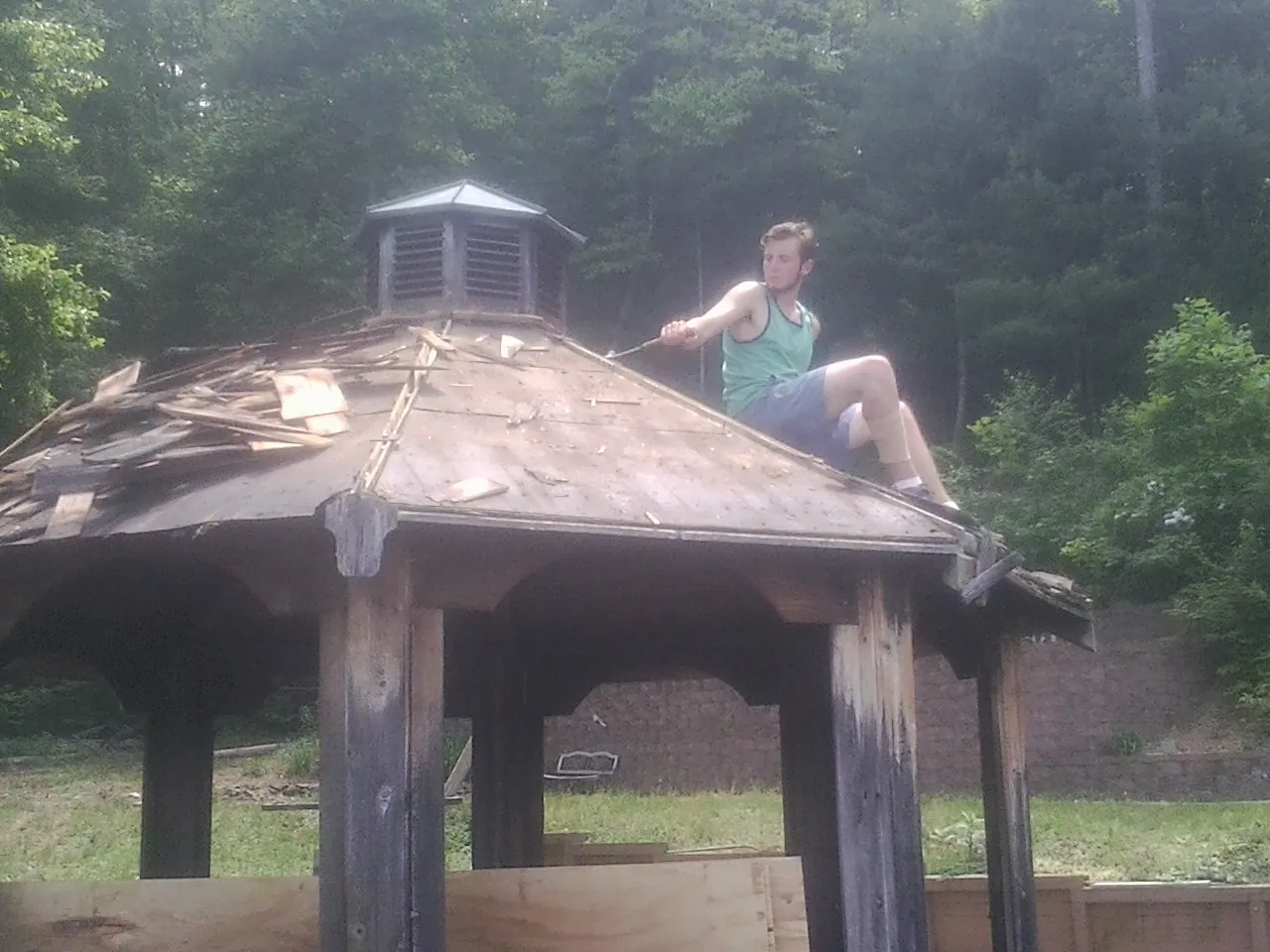 Tearing the old roof off a wooden gazebo before new shakes in Corunna