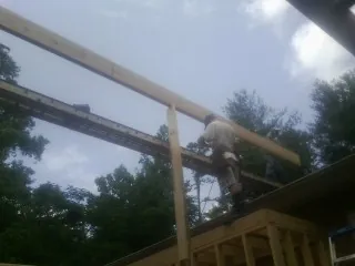 Carpenter setting a ridge beam over a new addition frame — Ice Dam Removal by Roofing Brothers in Corunna