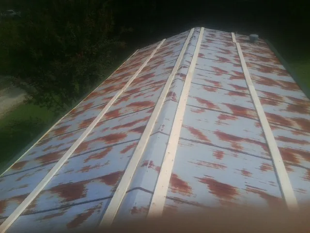 Rusted metal roof panels with new wood purlins before replacement — Storm Damage Roof Repair in Corunna by Roofing Brothers