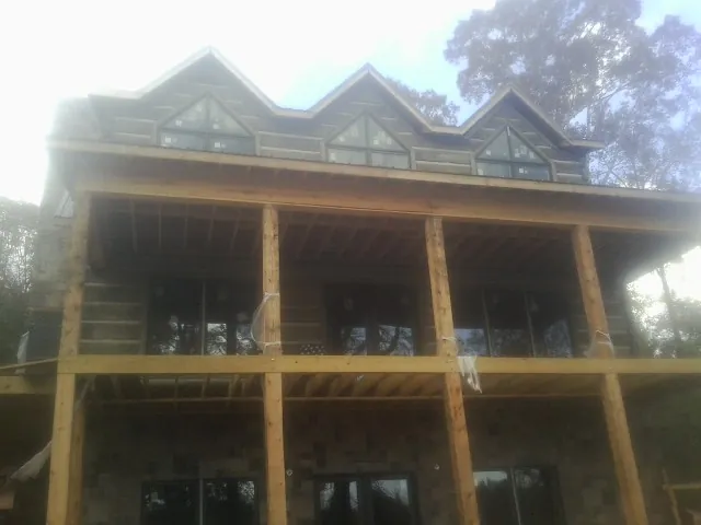 Dormers and porch framing on a large log home under construction — Roof Coating work by our crew in Corunna