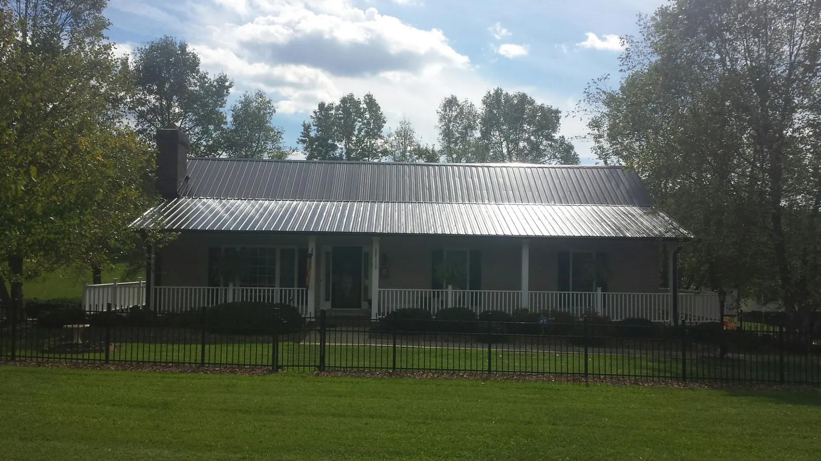 Gray metal roof on a brick ranch with a full width front porch — Gutter Guard Installation work by our crew in Corunna