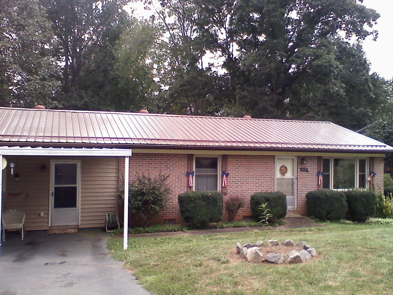 Bronze metal roof and carport on a brick ranch home — Roof Repair work by our crew in Corunna
