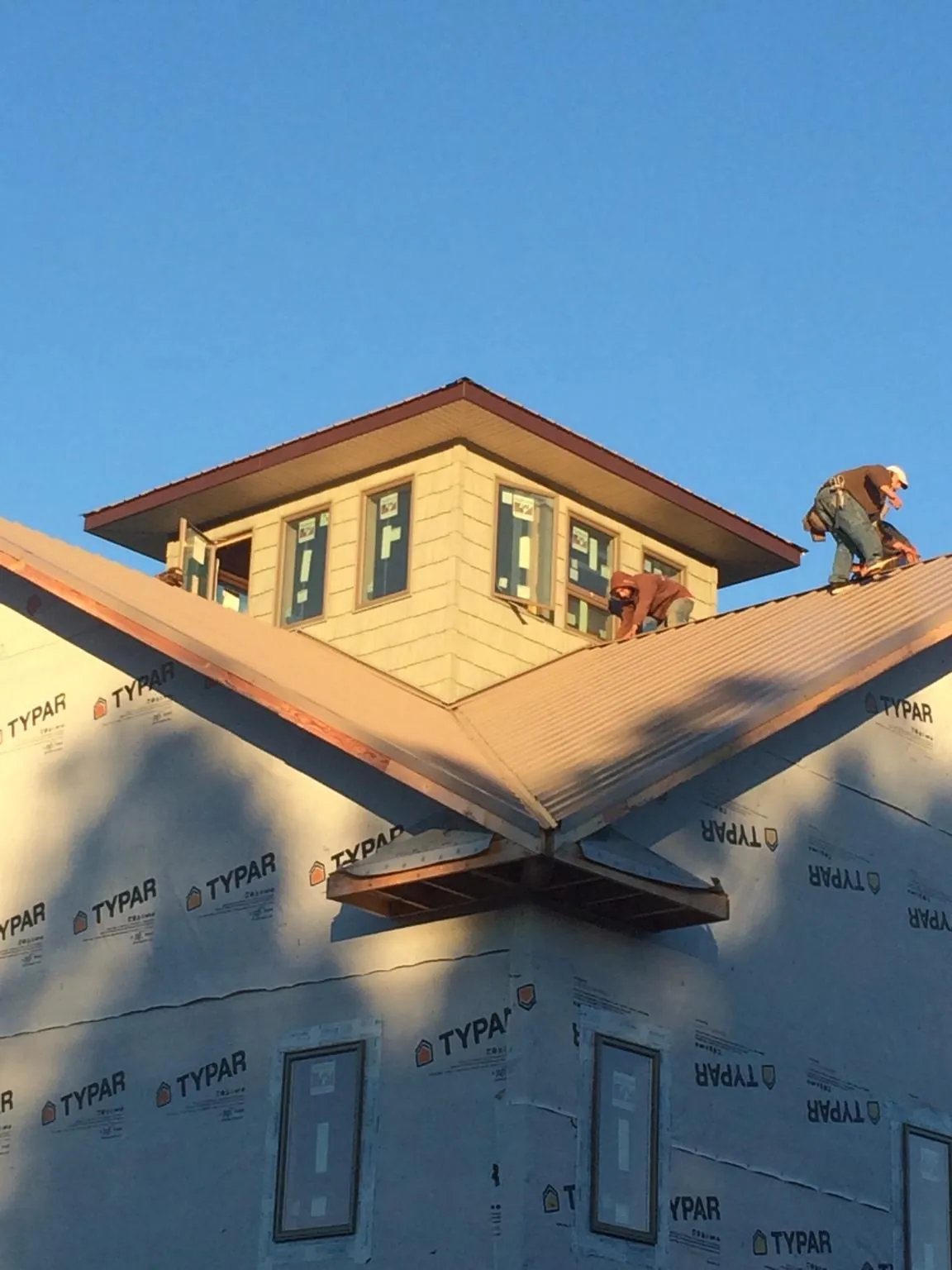 Roofers working around a rooftop cupola on a new metal roof at sunset — Roof Waterproofing in Corunna by Roofing Brothers